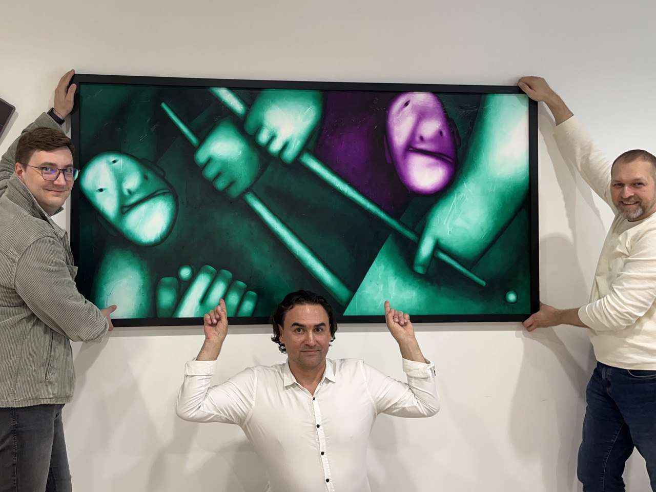 Billiard being installed at the SuperHow gallery in Vilnius, three people lifting and steadying the framed canvas on the wall